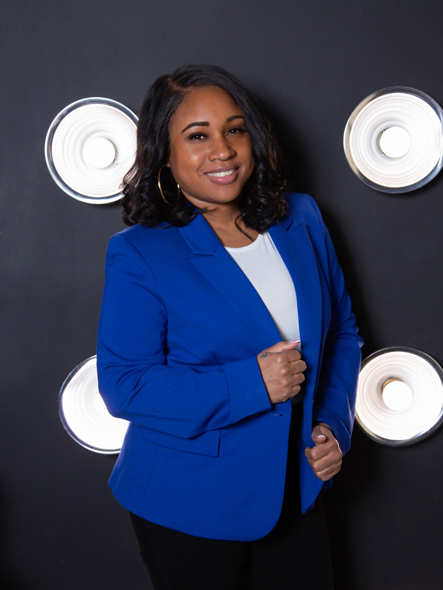 Shakira 'Sam' Moran, financial coach, smiling against studio lighting